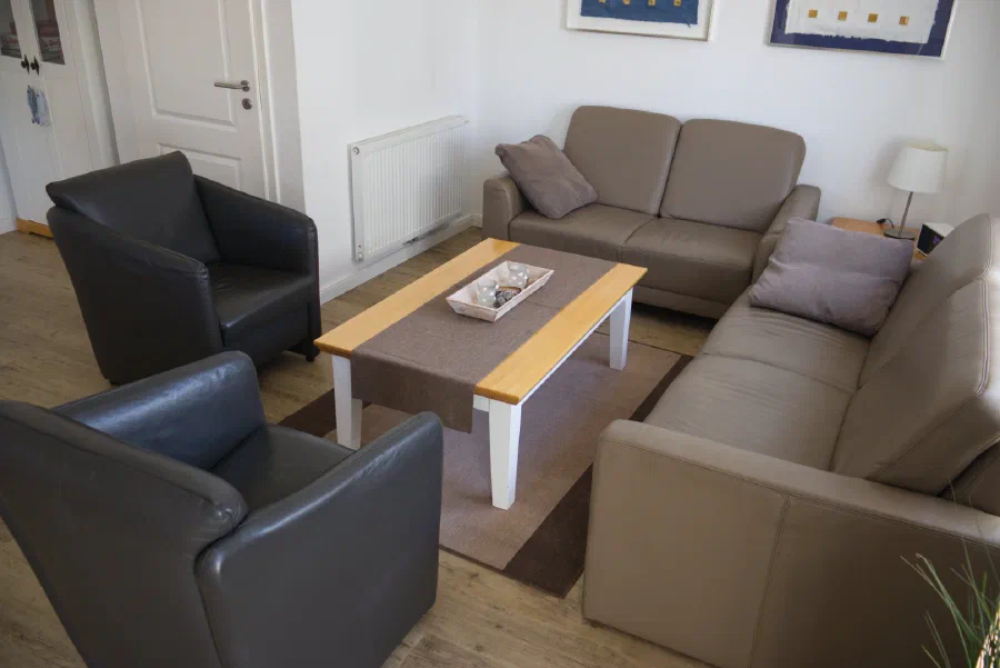 Wohnzimmer mit Couch und Sesseln rund um einen Couchtisch.